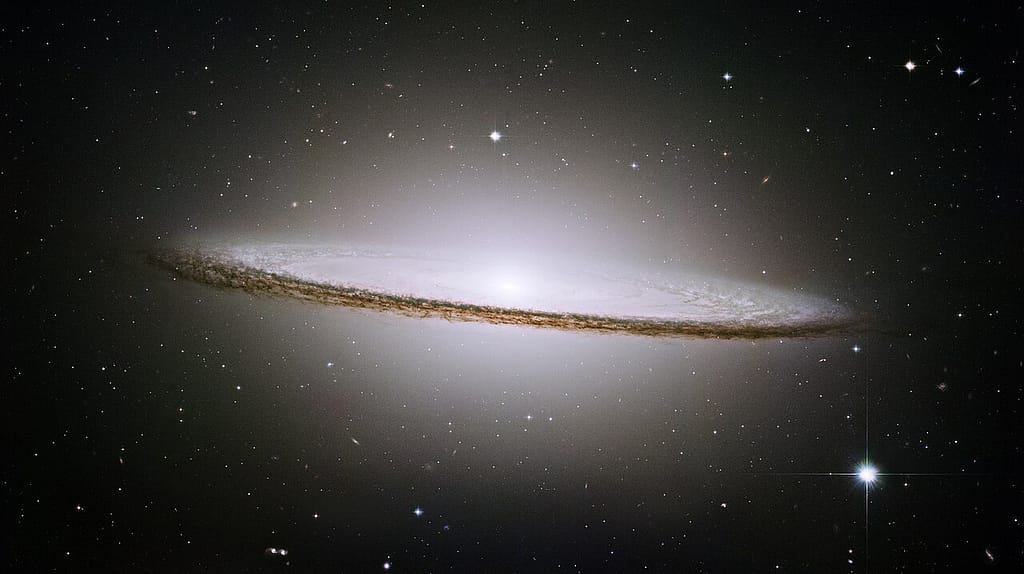 A Galáxia do Sombrero Imagem nítida da Galáxia do Sombrero, com seu núcleo brilhante e disco galáctico cercado por poeira escura, registrada pelo Hubble em contraste com o fundo estrelado do universo.