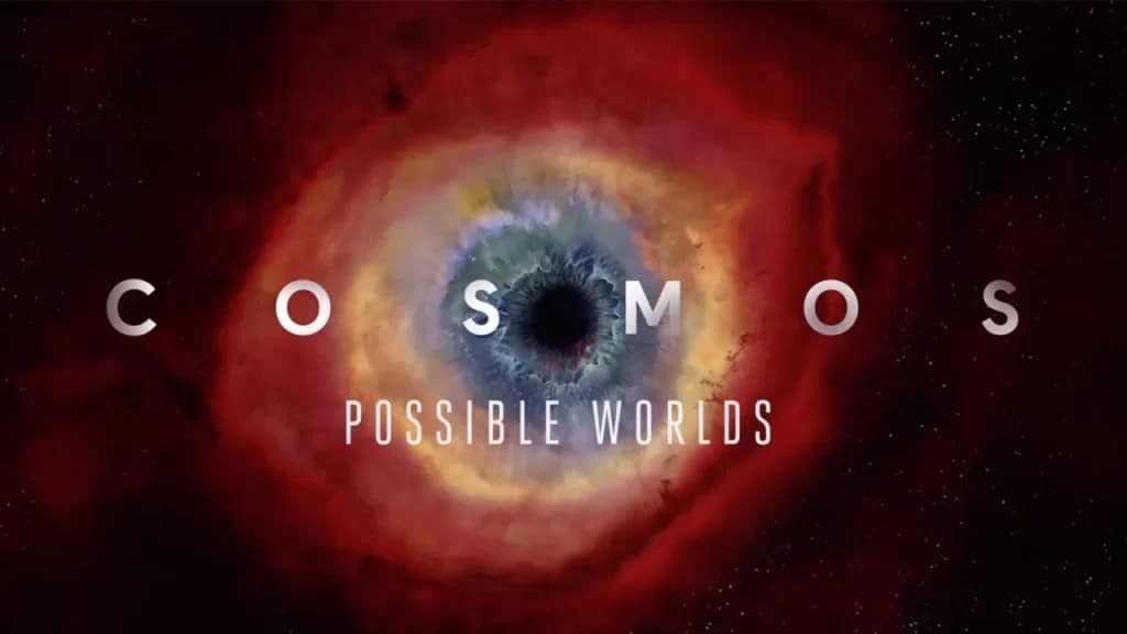 a icônica capa do programa de TV Cosmos,  A imagem exibe o Olho de Hélice (Helix Nebula), uma nebulosa planetária que se assemelha a um olho cósmico, com a palavra "COSMOS" destacada no centro.