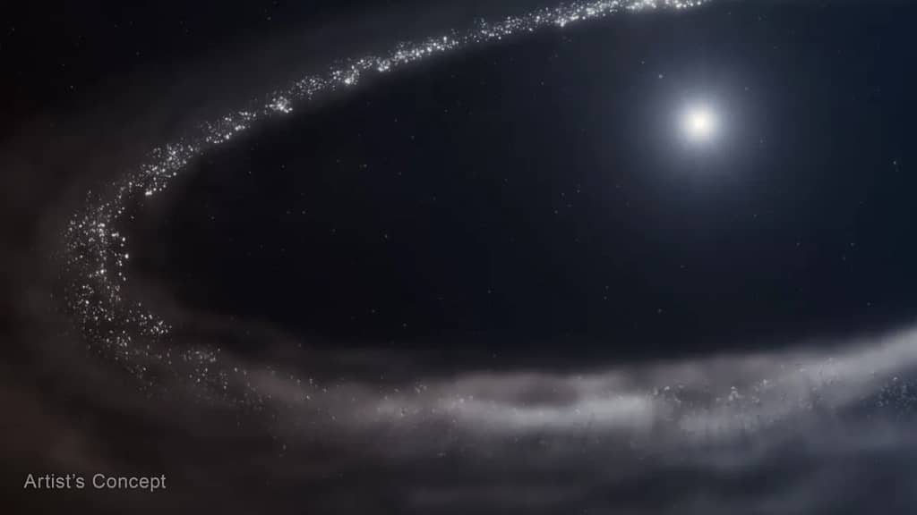 Ilustração da estrela semelhante ao Sol HD 181327 e seu disco de detritos ao redor. A estrela está no canto superior direito. Ela é cercada por um disco de detritos muito maior, que forma um caminho elíptico incompleto e é cortado à direita. Há uma enorme cavidade entre a estrela e o disco. O disco de detritos é mostrado em tons de cinza claro. Na parte superior e à esquerda, há pontos mais finos e distintos, em uma variedade de tamanhos. O disco parece mais nebuloso e esfumaçado na parte inferior. A estrela é branca brilhante no centro, com uma região azulada ao seu redor. O fundo do espaço é preto. A legenda 'Conceito Artístico' aparece no canto inferior esquerdo. James Webb Detecta Gelo de Água Cristalina