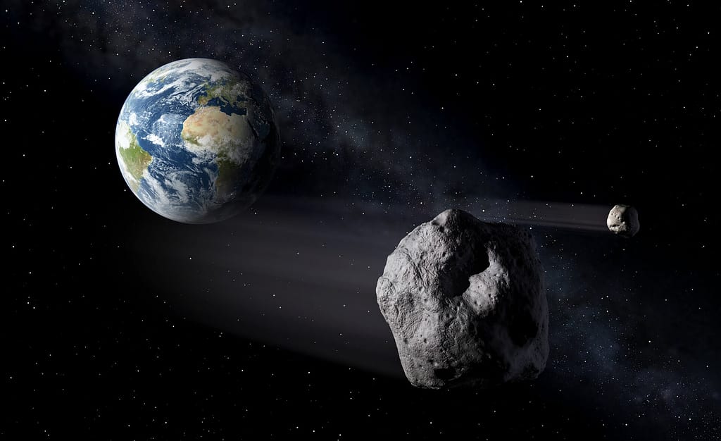 Ilustração mostrando a Terra vista do espaço com um asteroide se aproximando em sua direção, representando o conceito de defesa planetária e monitoramento de objetos próximos à Terra. Créditos: ESA.