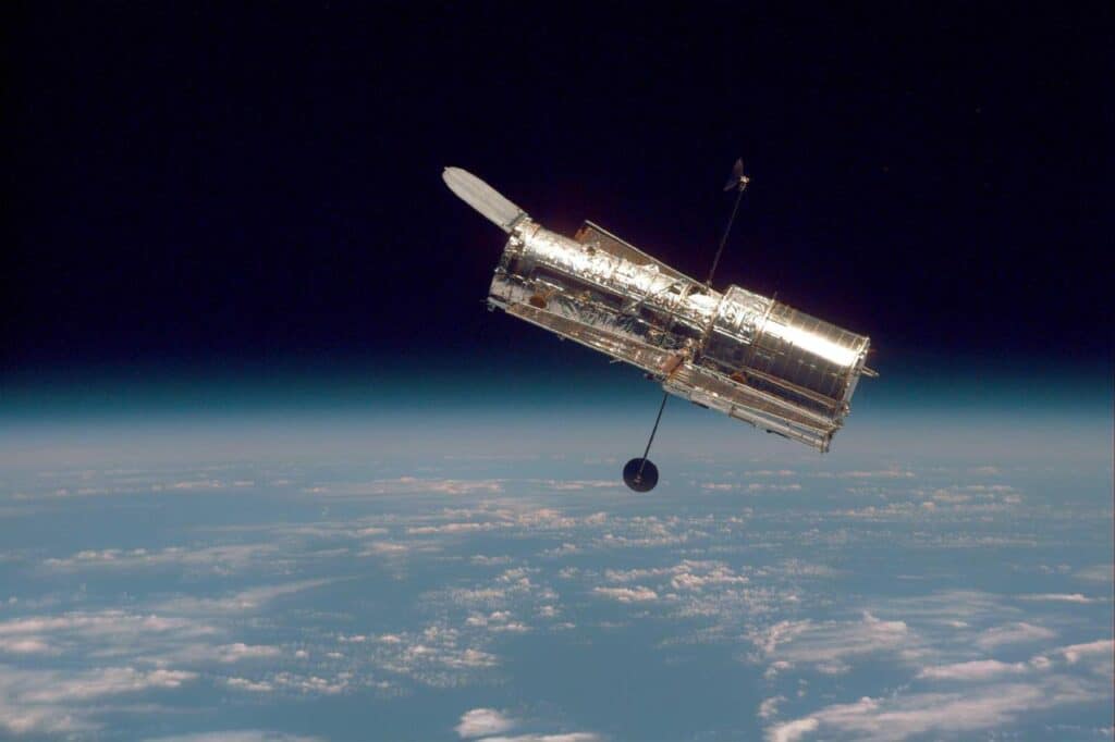 magem icônica da NASA do Telescópio Hubble, capturando a curvatura da Terra e a camada fina da atmosfera terrestre. A foto destaca a beleza da nossa planeta visto do espaço, com a linha do horizonte da Terra se misturando com a escuridão do cosmos.