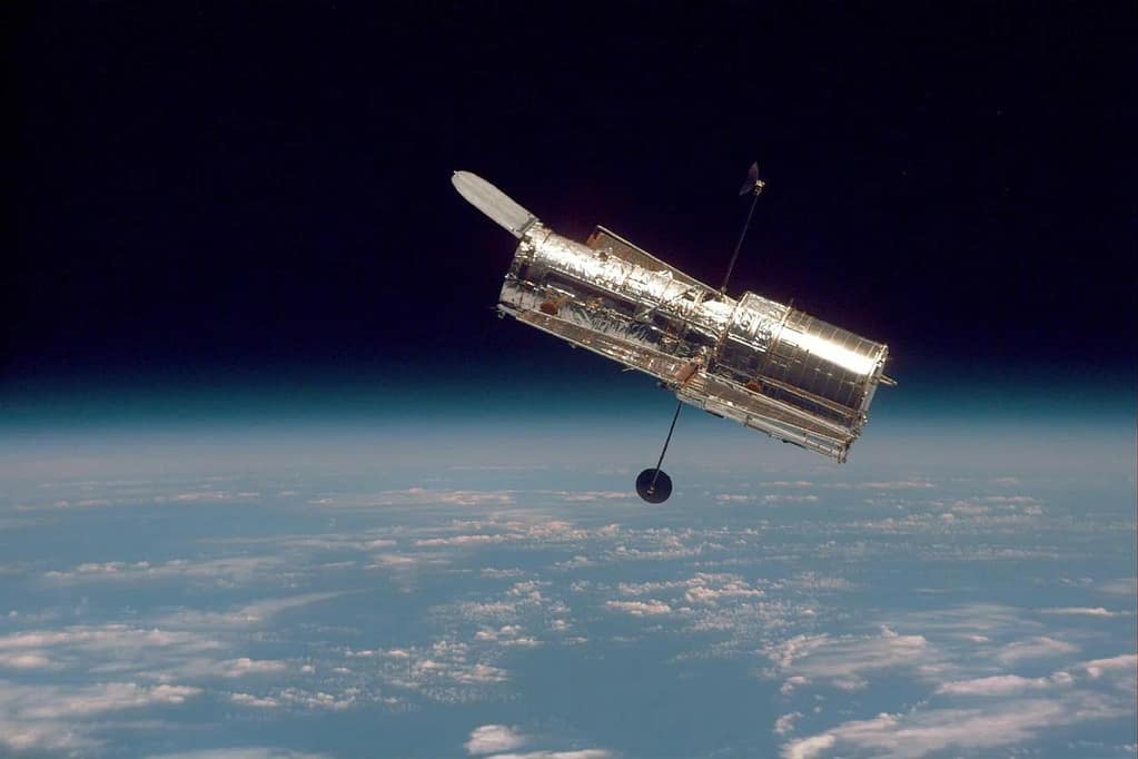 magem icônica da NASA do Telescópio Hubble, capturando a curvatura da Terra e a camada fina da atmosfera terrestre. A foto destaca a beleza da nossa planeta visto do espaço, com a linha do horizonte da Terra se misturando com a escuridão do cosmos.
