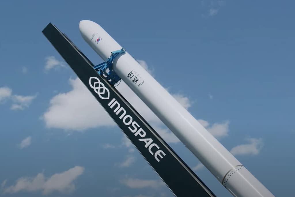 Foguete Hanbit-Nano da empresa sul-coreana Innospace em posição de lançamento, destacando seu corpo branco e logotipos, pronto para decolar.