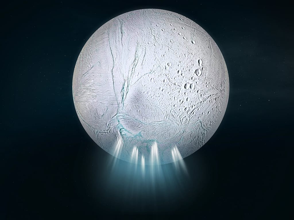 visão global de uma lua no espaço, com uma superfície muito branca coberta por marcas que lembram cicatrizes ou rachaduras. A partir das fendas na parte inferior da lua, emanam jatos brancos envoltos por um brilho azul difuso.