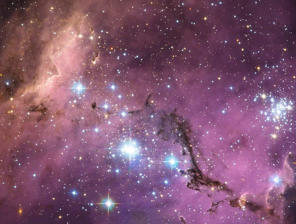 A cerca de 200 mil anos-luz da Terra, a Grande Nuvem de Magalhães — uma galáxia satélite da Via Láctea — flutua no espaço, em uma dança longa e lenta ao redor da nossa galáxia. Enormes nuvens de gás em seu interior colapsam lentamente, formando novas estrelas. Por sua vez, essas estrelas iluminam as nuvens de gás em um espetáculo de cores, visível nesta imagem do Telescópio Espacial Hubble.