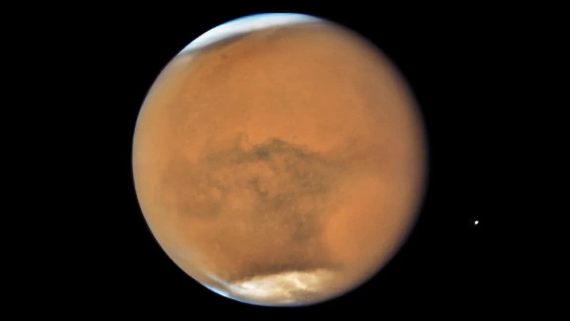 Planeta Marte capturado pelo Telescópio Hubble, com ênfase nas calotas polares. As regiões polares de Marte são visíveis com uma camada de gelo, contrastando com a superfície avermelhada do planeta. A imagem revela uma visão detalhada de Marte e suas variações climáticas.