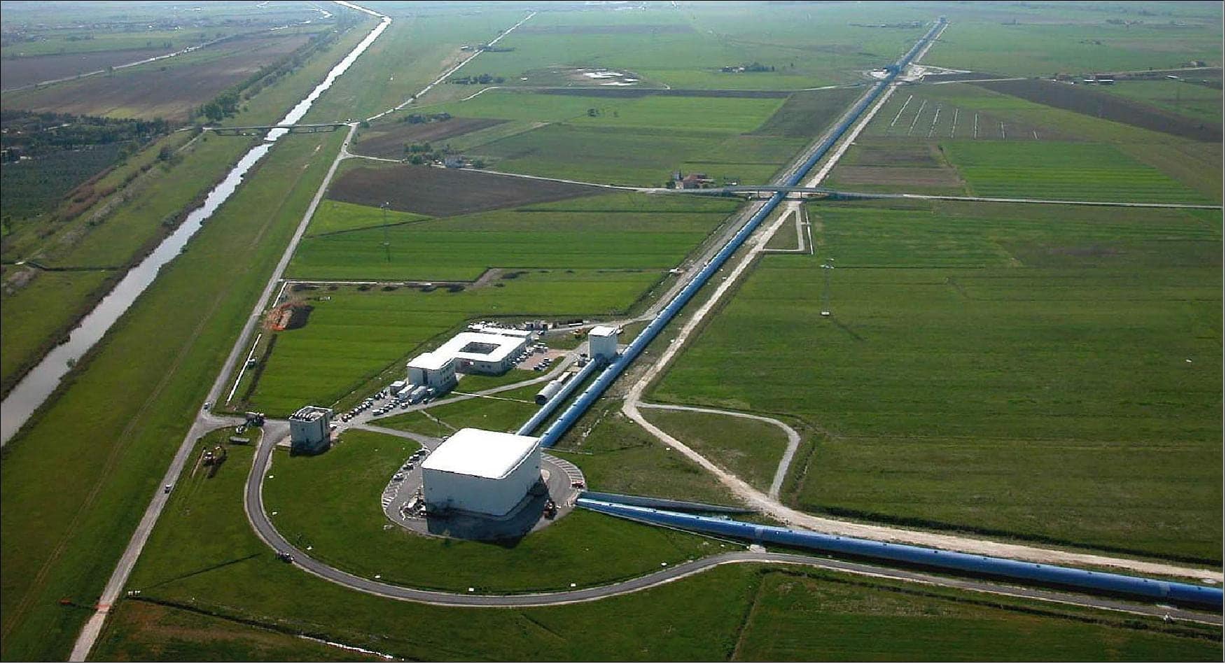 Imagem aérea do Observatório Ligo, , mostrando os longos braços perpendiculares do interferômetro de ondas gravitacionais, cercado por áreas verdes e estruturas técnicas.