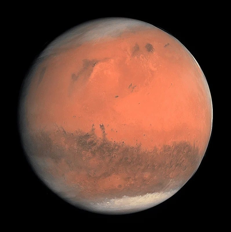 Imagem real de Marte capturada pelo Telescópio Espacial Hubble, mostrando suas calotas polares esbranquiçadas devido ao gelo e sua superfície avermelhada característica. As calotas polares de Marte são compostas principalmente de gelo de dióxido de carbono e água, variando de tamanho conforme as estações do planeta.