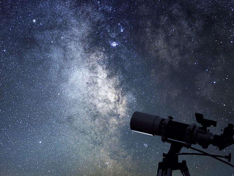 Pessoa observando o céu noturno com telescópio, simbolizando a conexão entre astronomia e o ser humano