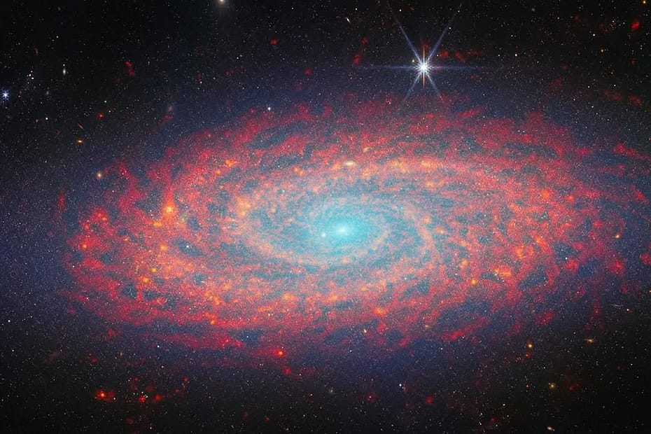 galáxia NGC 2090 capturada pela NASA. A galáxia, localizada a cerca de 100 milhões de anos-luz da Terra, exibe uma estrutura espiral com cores vibrantes, com áreas de formação estelar em tons de azul e roxo, contrastando com o fundo escuro do espaço profundo. O brilho das estrelas jovens e das regiões de gás e poeira é claramente visível, destacando a complexidade e beleza da galáxia.