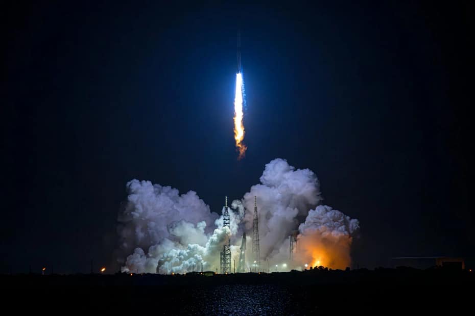 Primeiro voo de teste noturno do foguete New Glenn da Blue Origin, alcançando a órbita em sua tentativa inicial. A imagem captura o foguete saindo do pad de lançamento, com uma enorme coluna de fogo sendo gerada pelos potentes motores. O brilho intenso destaca-se contra o céu escuro da noite.