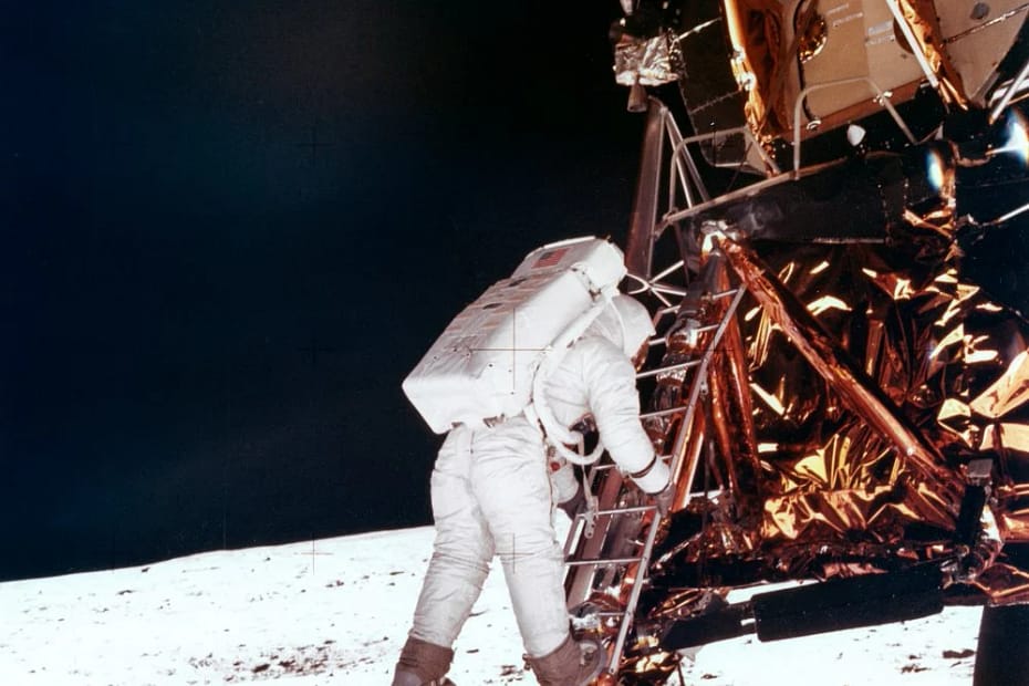 Imagem icônica de Buzz Aldrin descendo do módulo lunar Eagle durante a missão Apollo 11, em 1969. Ele está de traje espacial completo, com os pés quase tocando a superfície lunar pela primeira vez. A foto, tirada por Neil Armstrong, simboliza um dos momentos mais históricos da exploração espacial, quando o homem pisou pela primeira vez na Lua