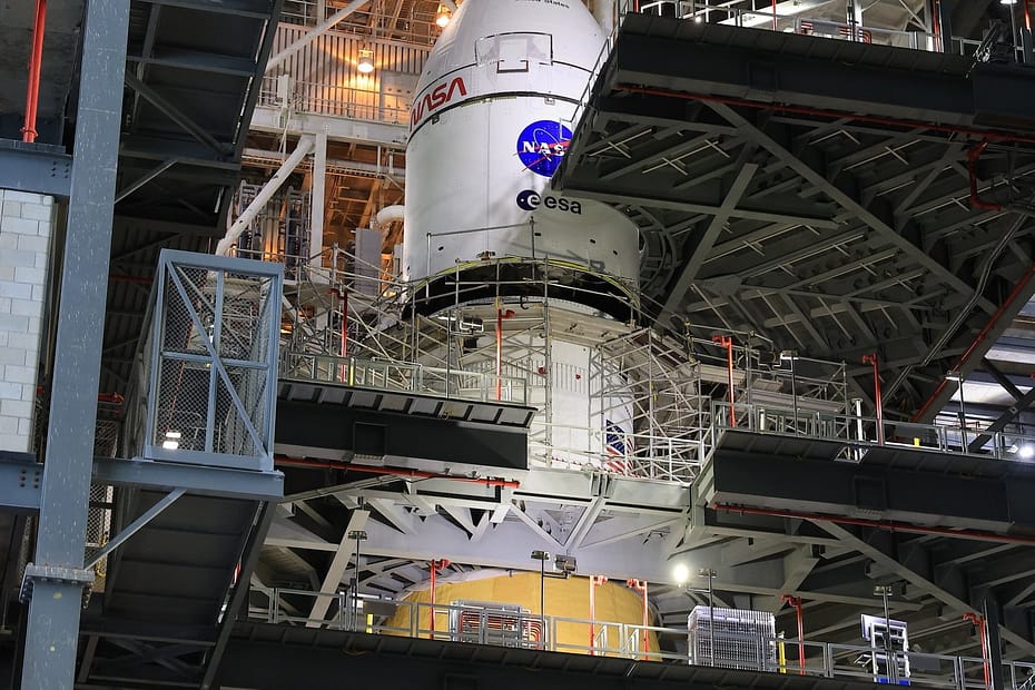 Vista de longe da nave Orion sendo elevada pelo guindaste no local de lançamento, durante o processo de montagem no foguete SLS para a missão Artemis 2. Créditos: NASA