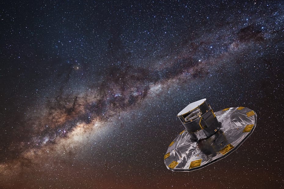 Imagem artística mostrando o Telescópio Espacial Gaia mapeando as estrelas da Via Láctea. A espaçonave aparece em primeiro plano, refletindo a luz das estrelas, enquanto ao fundo se estende um vasto campo estelar repleto de pontos luminosos, representando o trabalho do Gaia na criação do mapa tridimensional mais detalhado da nossa galáxia.