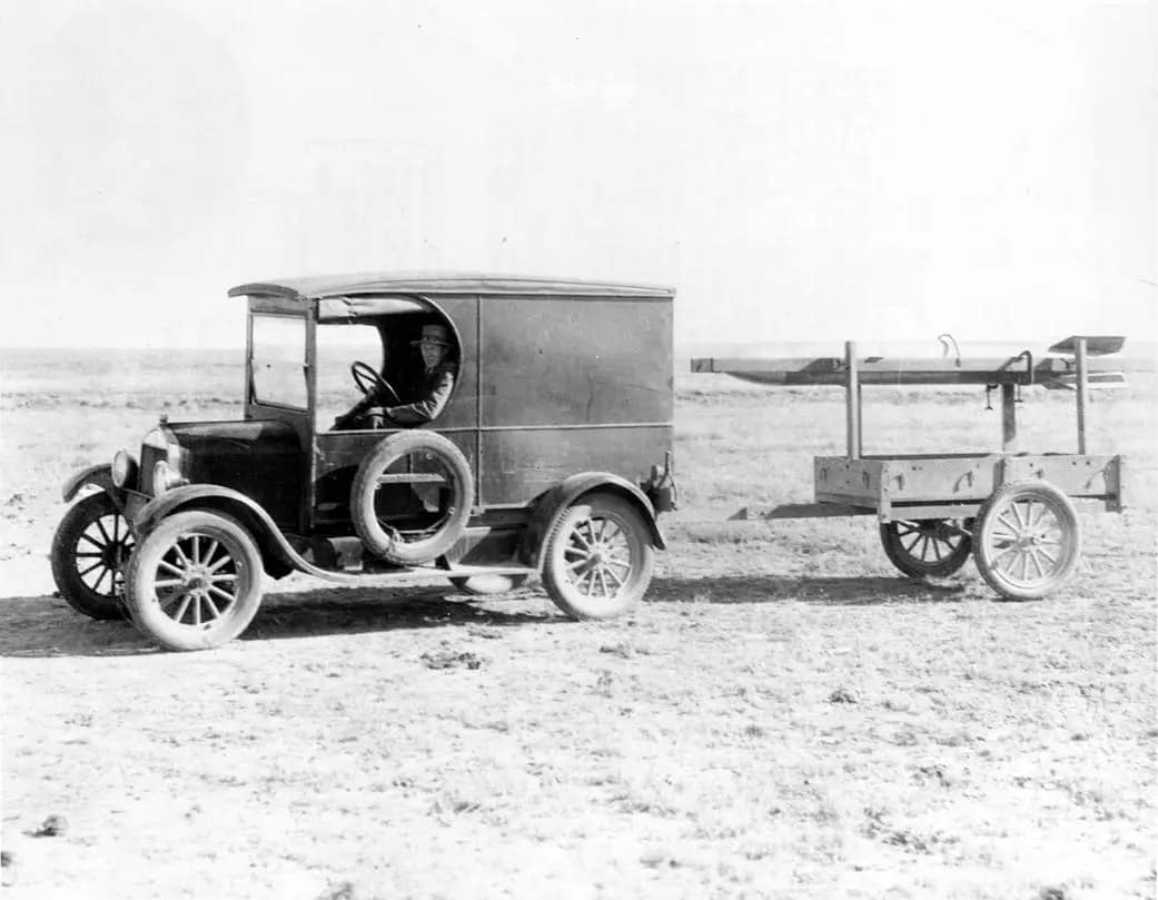e Dr. Robert H. Goddard rebocando seu foguete até a torre de lançamento, atrás de um caminhão Ford Modelo A, na década de 1930, a 15 milhas a noroeste de Roswell, Novo México. O Dr. Goddard é reconhecido como o 'Pai da Astronáutica Americana' e um pioneiro na exploração teórica do espaço.