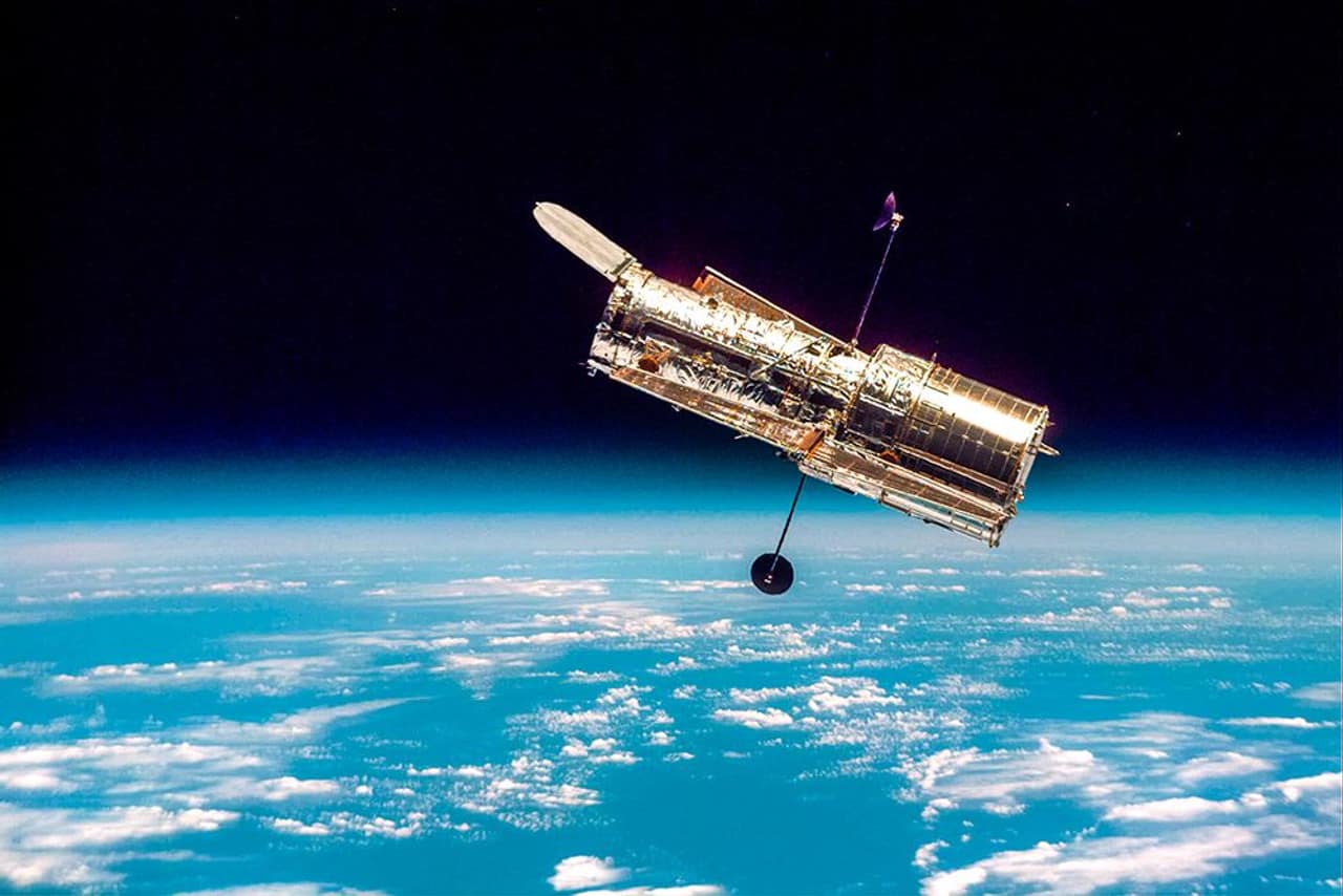 Telescópio Espacial Hubble em órbita da Terra, com o azul vibrante da atmosfera e a curvatura do planeta ao fundo, simbolizando sua posição estratégica fora da atmosfera.