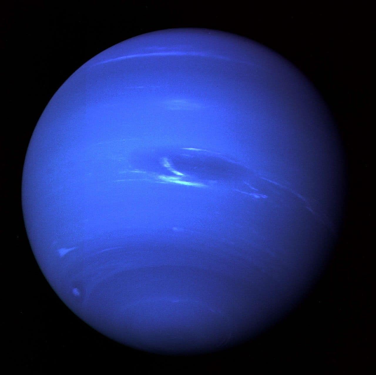 Imagem de Netuno registrada pela Voyager 2 da NASA em 1989, mostrando o planeta gasoso azul, o mais distante do Sistema Solar. Netuno possui ventos supersônicos, anéis tênues, 14 luas conhecidas e temperatura média de -214 °C.