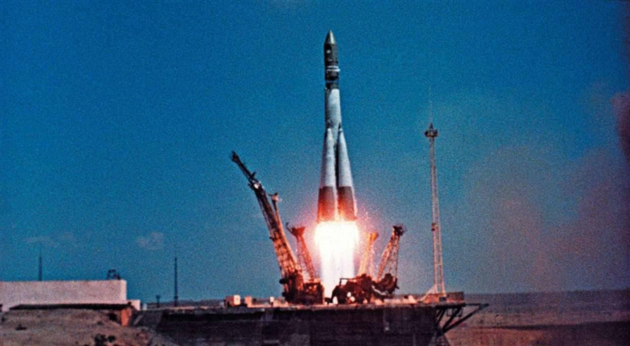 A espaçonave Vostok 1, com Yuri Gagarin a bordo, é lançada do Cosmódromo de Baikonur em 12 de abril. O foguete sobe em meio a uma enorme nuvem de fumaça e chamas, marcando o início do primeiro voo tripulado ao espaço e um momento histórico para a exploração espacial.