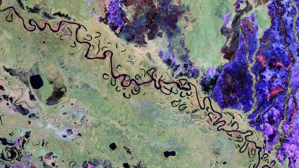 Imagem de radar capturada pelo satélite Biomass da ESA mostrando parte da Bolívia, com áreas de floresta tropical, planícies alagadas, pastagens e rios, destacadas por diferentes cores. A imagem revela os efeitos do desmatamento para expansão agrícola e contribui para o monitoramento do carbono florestal e mudanças no ecossistema.