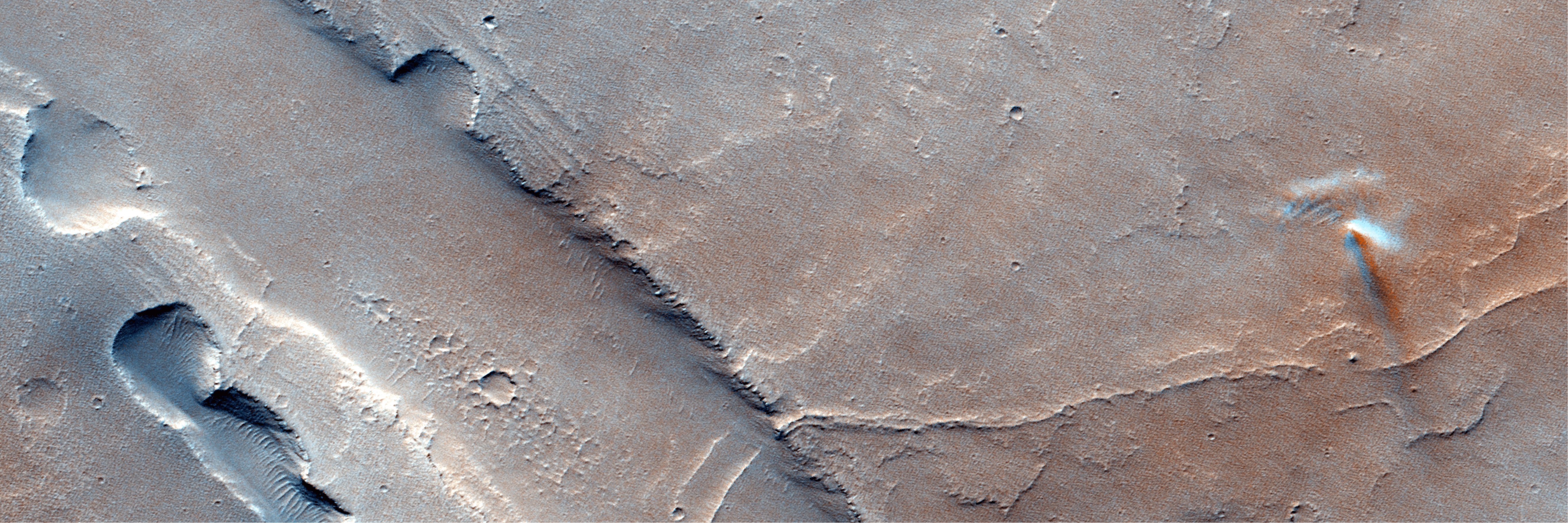 Uma imagem de satélite colorida de Marte mostra uma paisagem plana e empoeirada, com um discreto redemoinho de poeira — uma pequena coluna de poeira semelhante a um tornado — projetando uma sombra sutil enquanto se move pela superfície. O redemoinho aparece como uma faixa vertical clara sobre o terreno avermelhado, com crateras rasas e pequenas elevações visíveis ao redor.